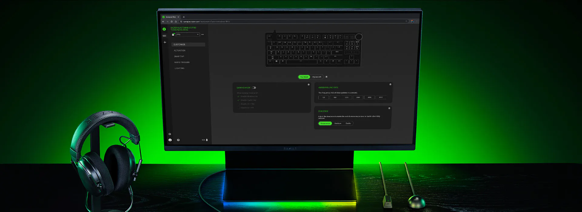 Razer Synapse Web בדפדפן על מסך, עם אוזניות ותאורת כרומה ירוקה על שולחן העבודה